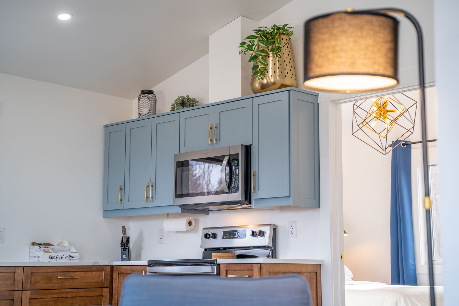 Cottage kitchen area, with fridge, sink under the window, stove, oven, microwave, cupboards, and a kitchen table.