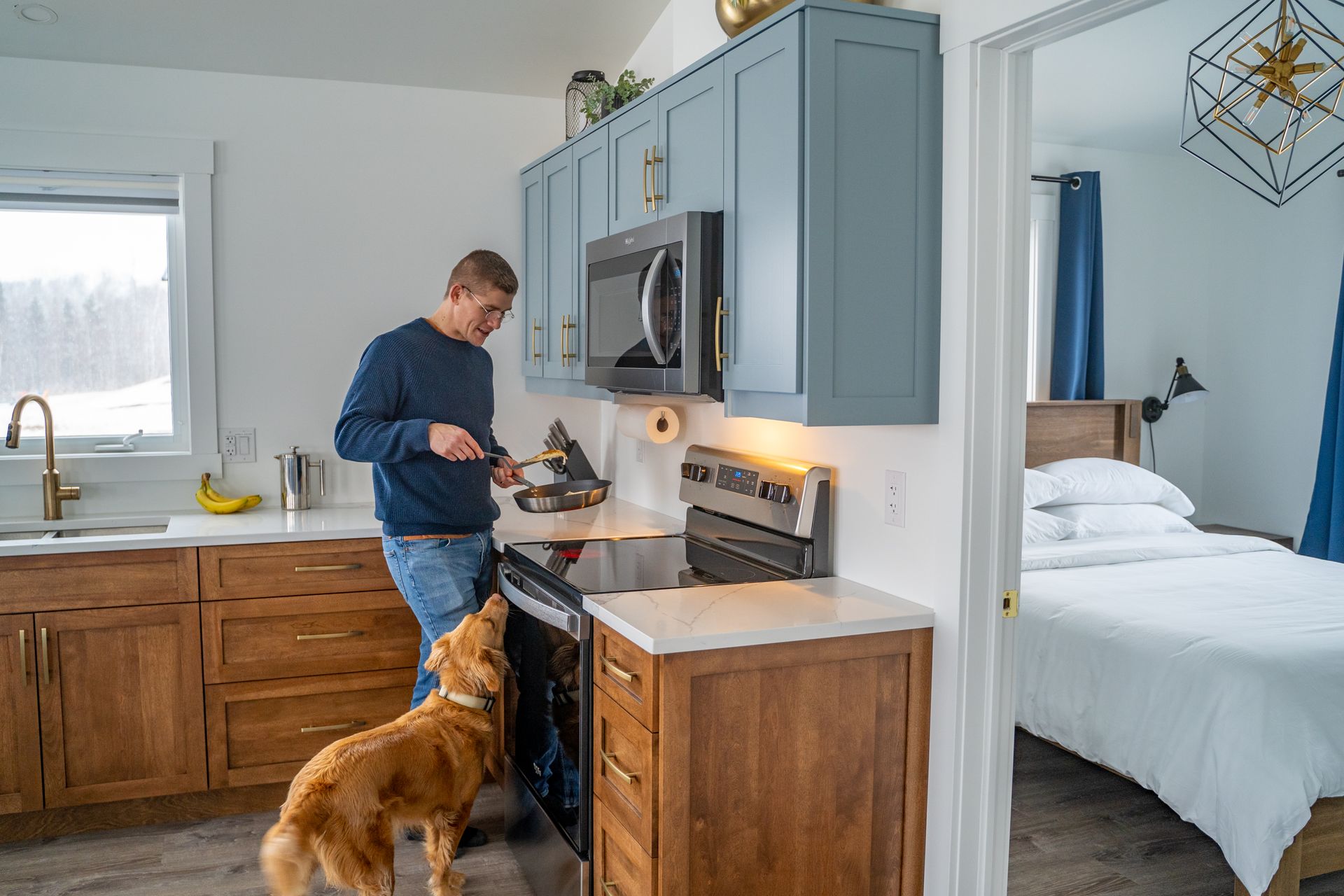 Cottage kitchen area, with fridge, sink under the window, stove, oven, microwave, cupboards, and a kitchen table.