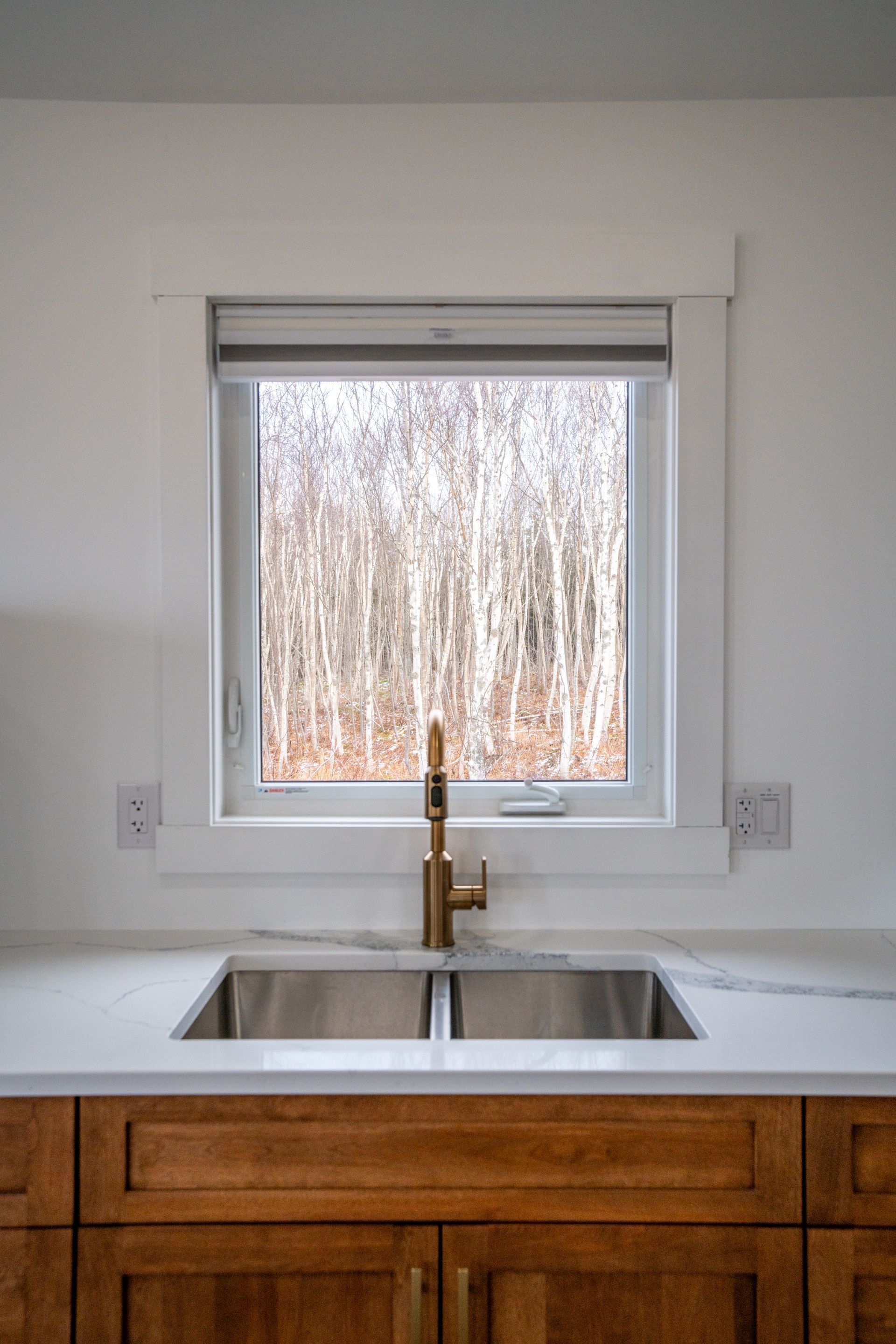 Cottage kitchen area, with fridge, sink under the window, stove, oven, microwave, cupboards, and a kitchen table.