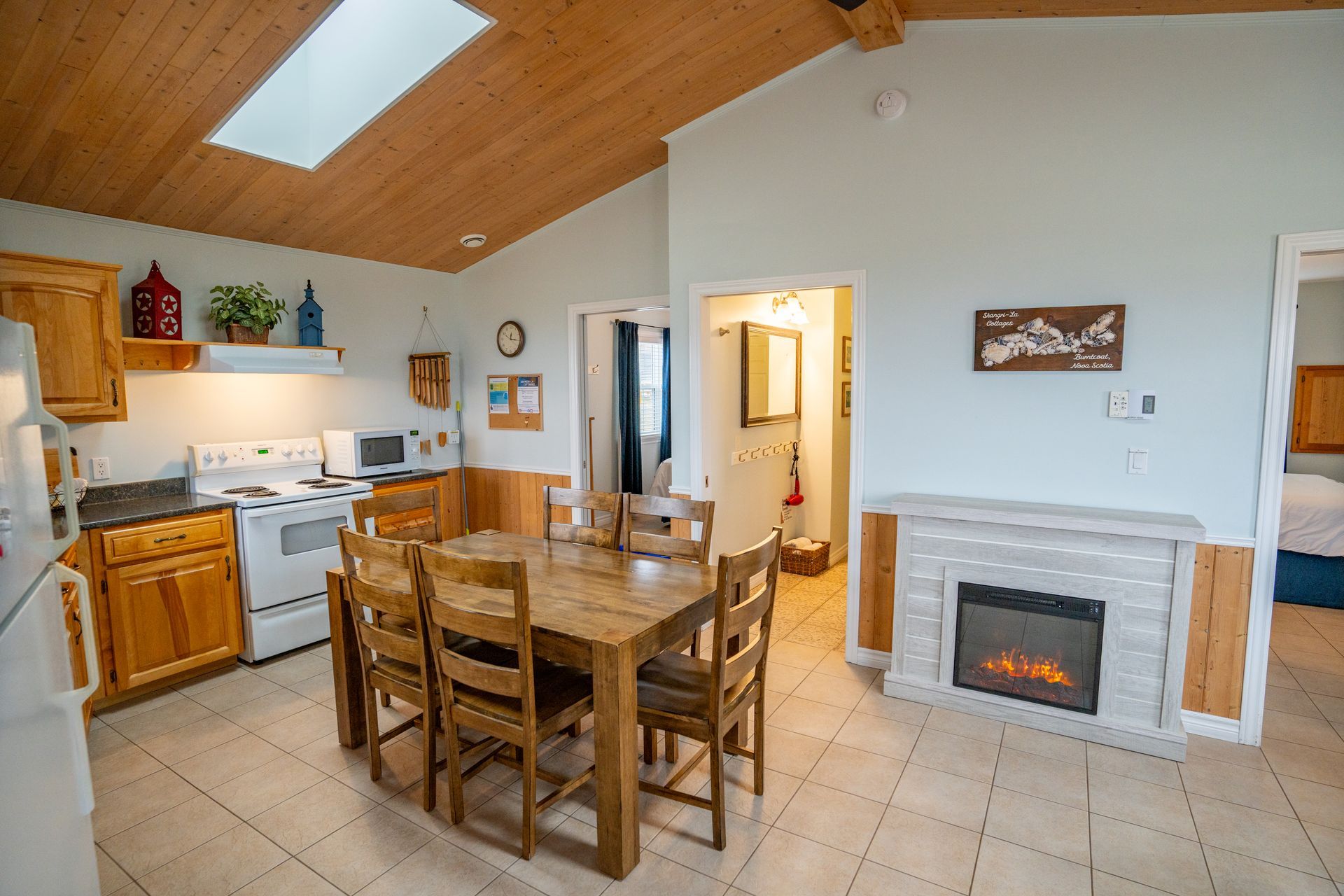 Cottage kitchen area, with fridge, sink, stove, oven, microwave, cupboards, and a kitchen table and a fireplace