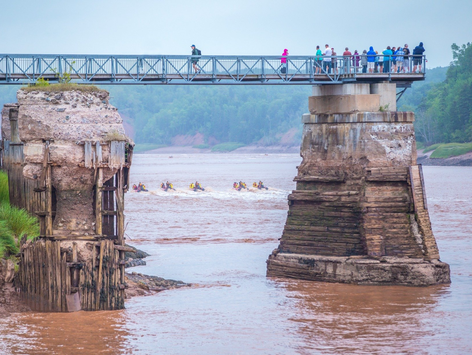 fundy tidal interpretive center's bridge that over looks the shubie river and all of the river rafters enjoying the rapids.