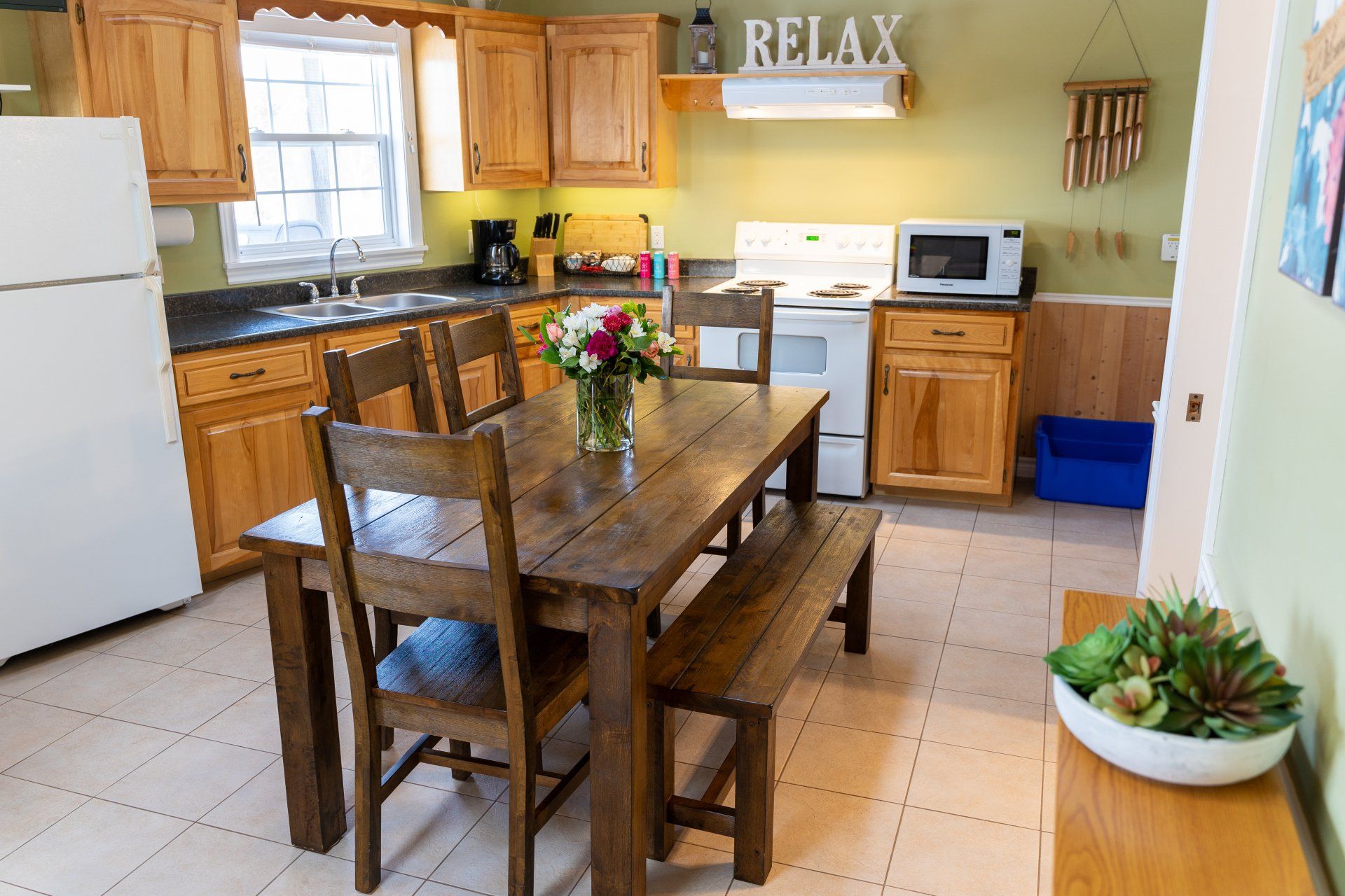 cottage kitchen with large wooden table, open concept dining and living room with vaulted ceilings and sky lights