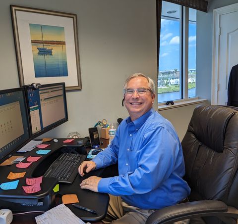A financial advisor shows a laptop screen to a smiling couple in an office, pointing to the screen.