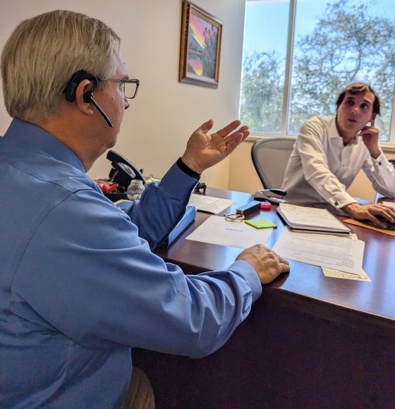 Real estate agent showing paperwork to a smiling couple in a living room setting.