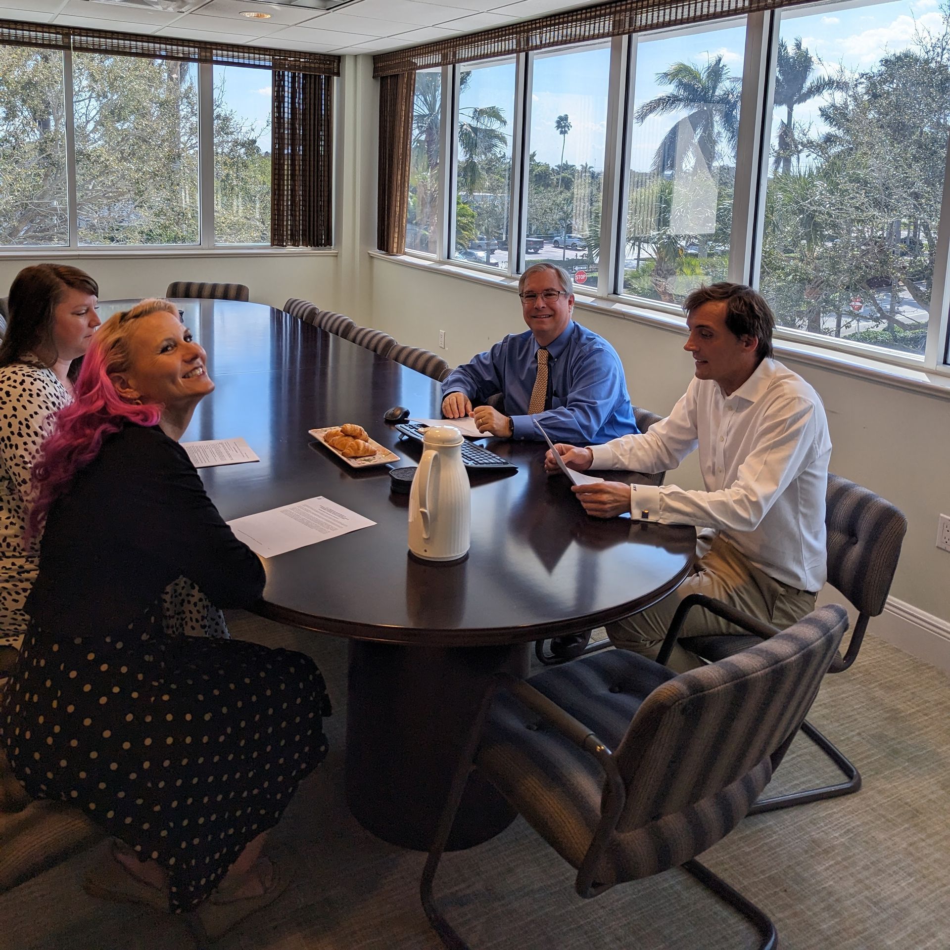 Two people shaking hands over a desk with a laptop and documents.