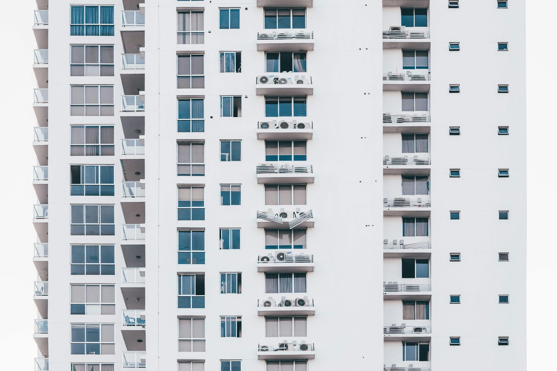 White high-rise apartment building with balconies and windows.
