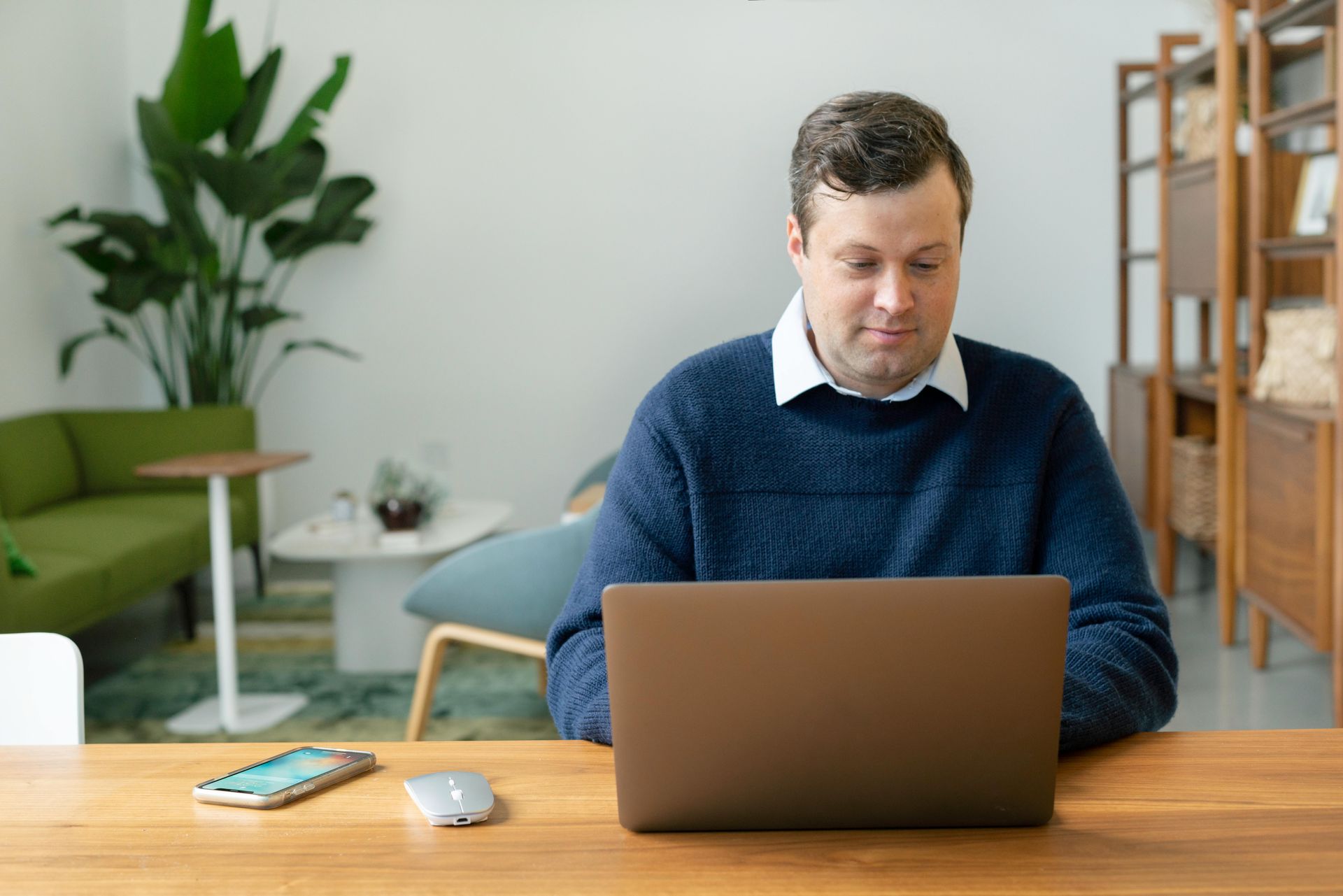 A man is smiling while sitting in front of a laptop computer.