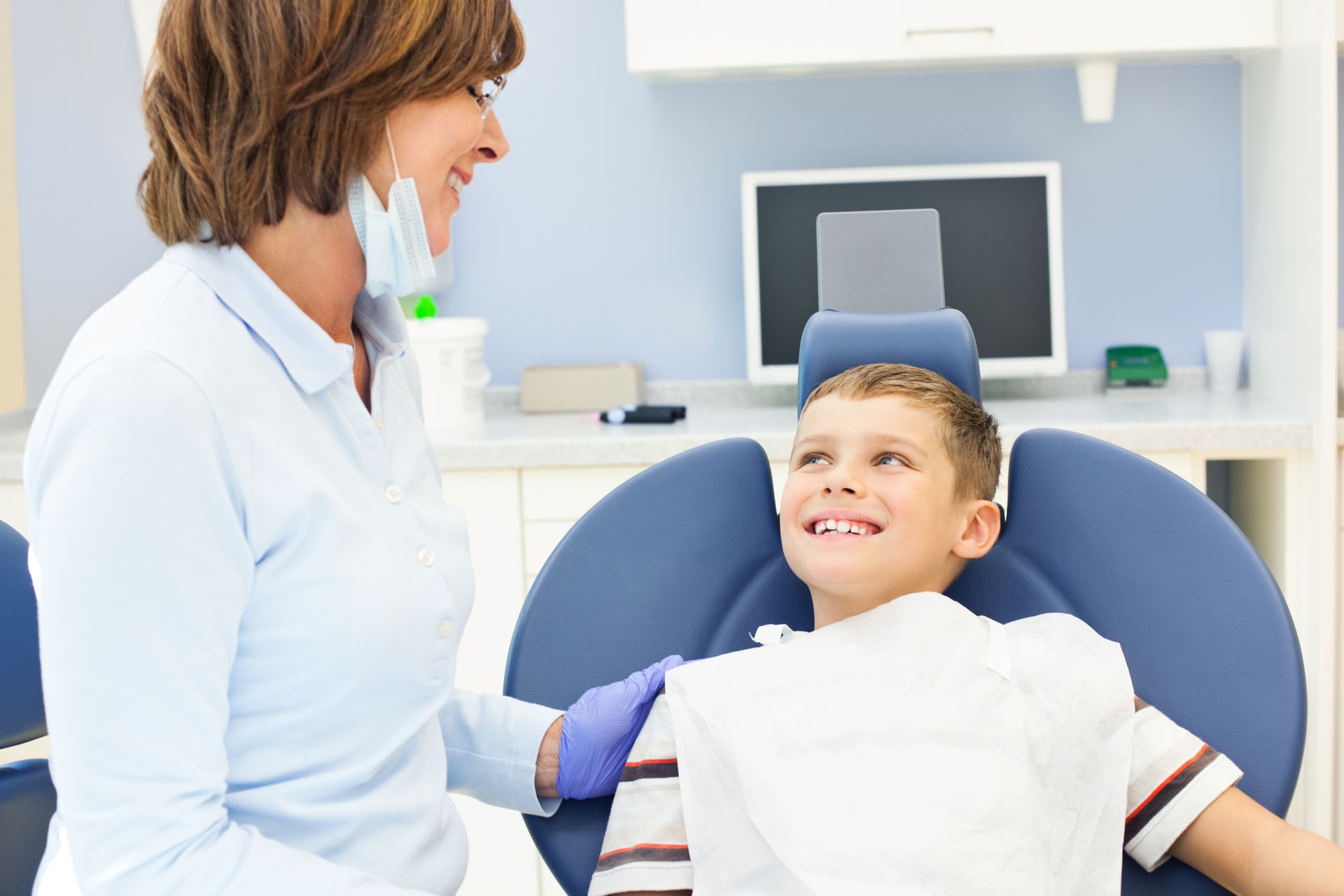 A young boy smiles in a dentist’s chair, showcasing pediatric dentists’ friendly environment.