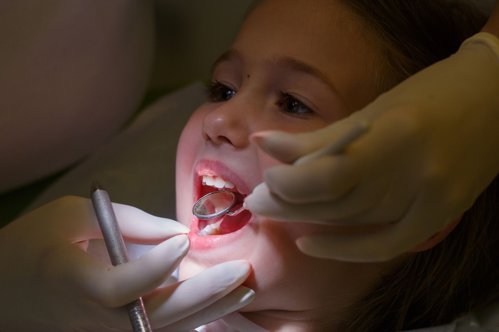 A young girl at a pediatric dentist's office being examined for white filling treatment. A young girl at a pediatric dentist's office being examined for white filling treatment.
