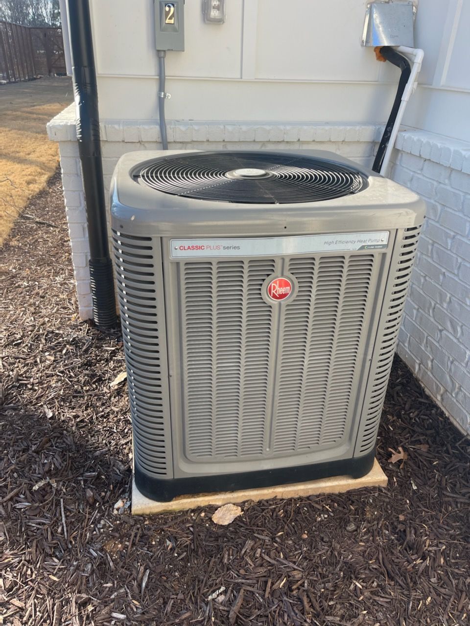 an air conditioner is sitting on a wooden platform outside of a house
