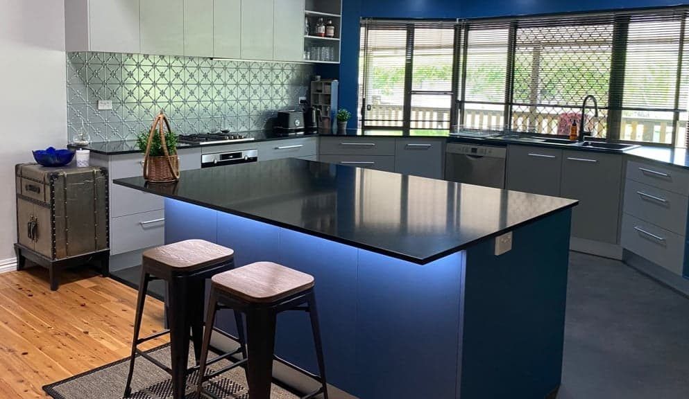 A Kitchen With Blue Cabinets, a Black Island Countertop — Craftsmen Kitchens In Monkland, QLD