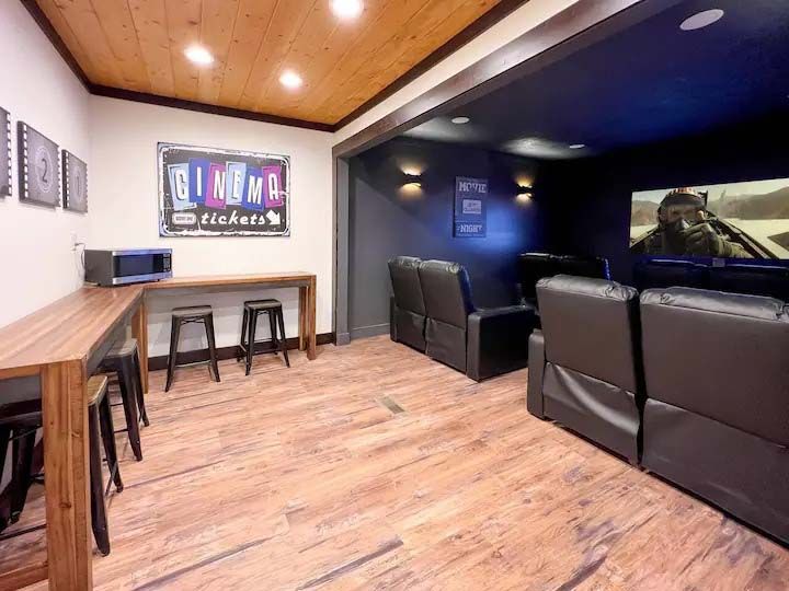 Home theater with bar seating, microwave, black recliners, and movie screen.