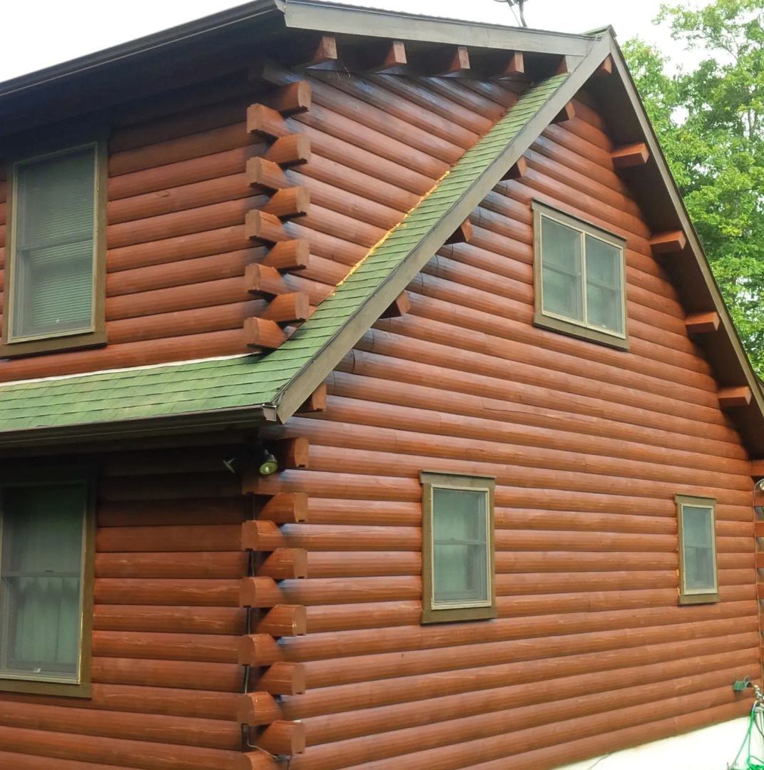 Brown log cabin with green roof and windows.