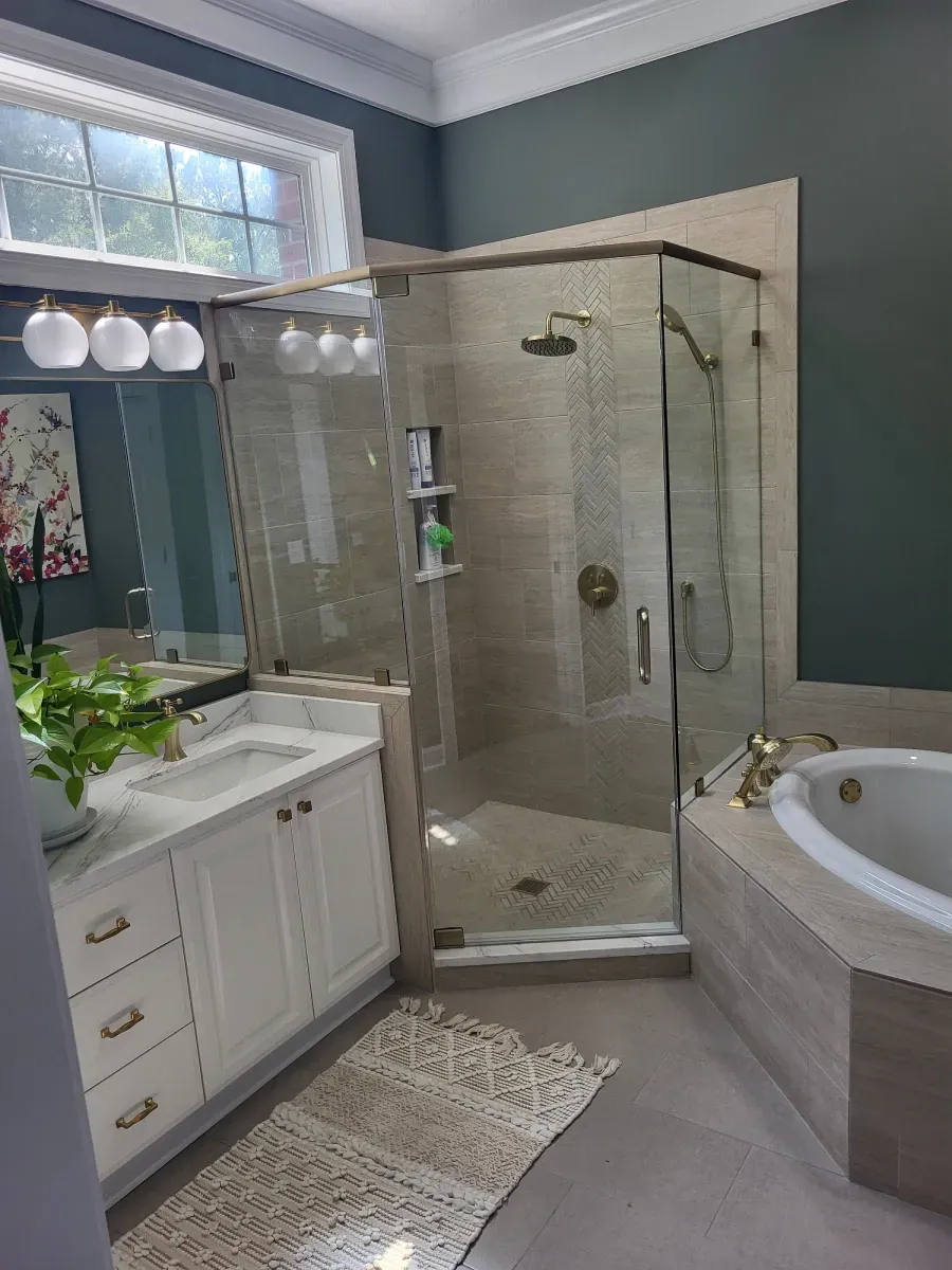 Bathroom with a shower stall, vanity, and bathtub. Light-colored tiles and walls, white vanity, and dark teal accent wall.