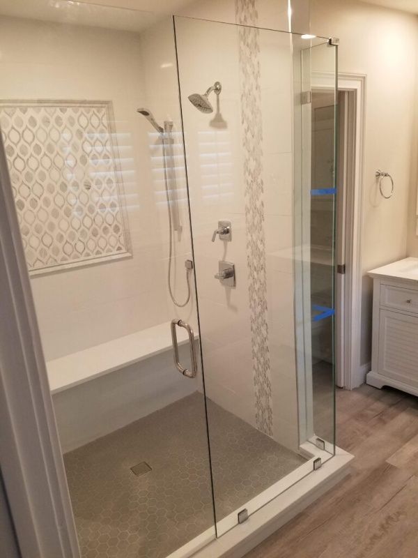Modern, glass-walled shower with a built-in bench. The shower has a patterned accent strip, two shower heads, and silver fixtures.