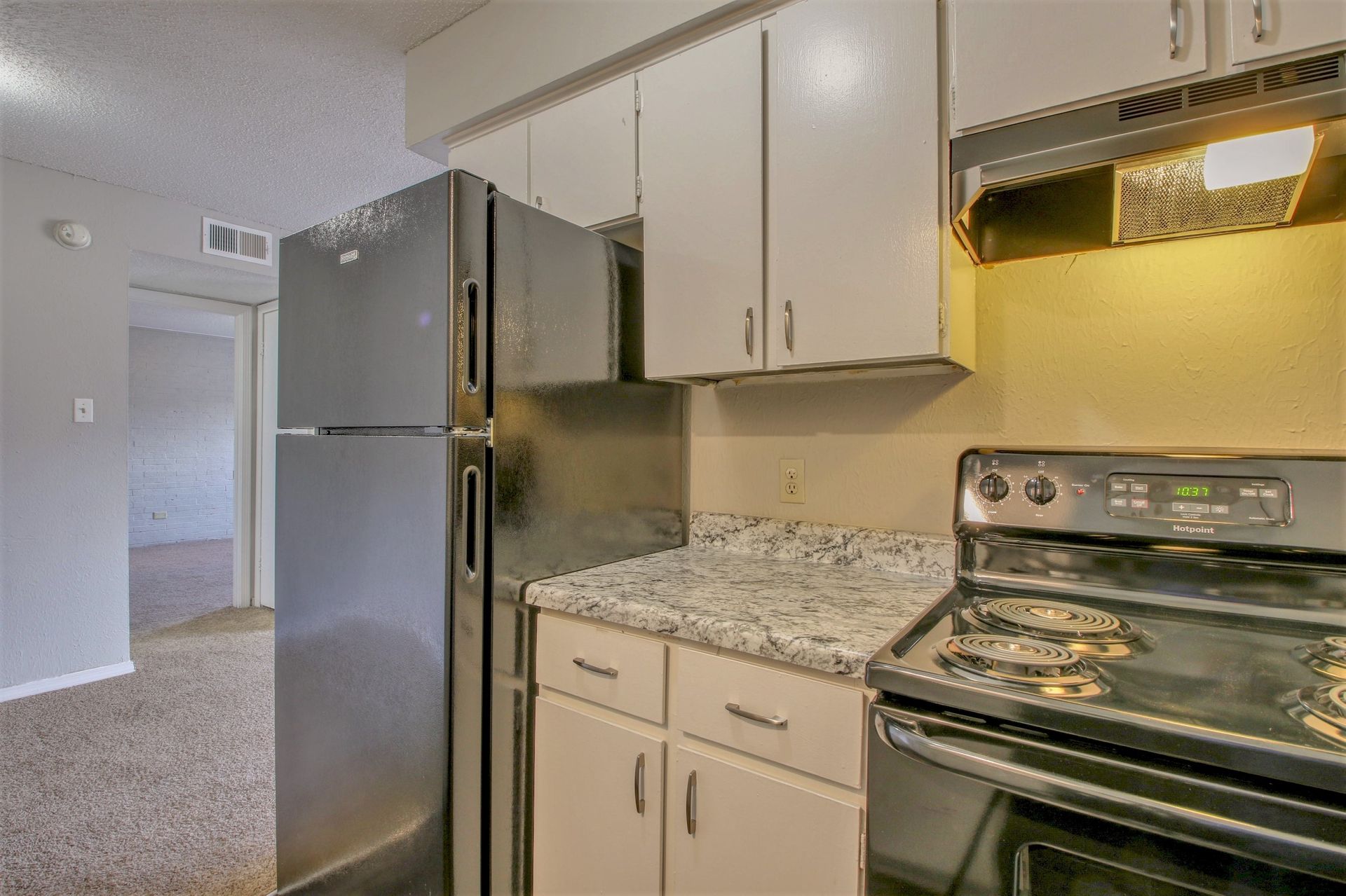 A kitchen with a refrigerator , stove , and cabinets.