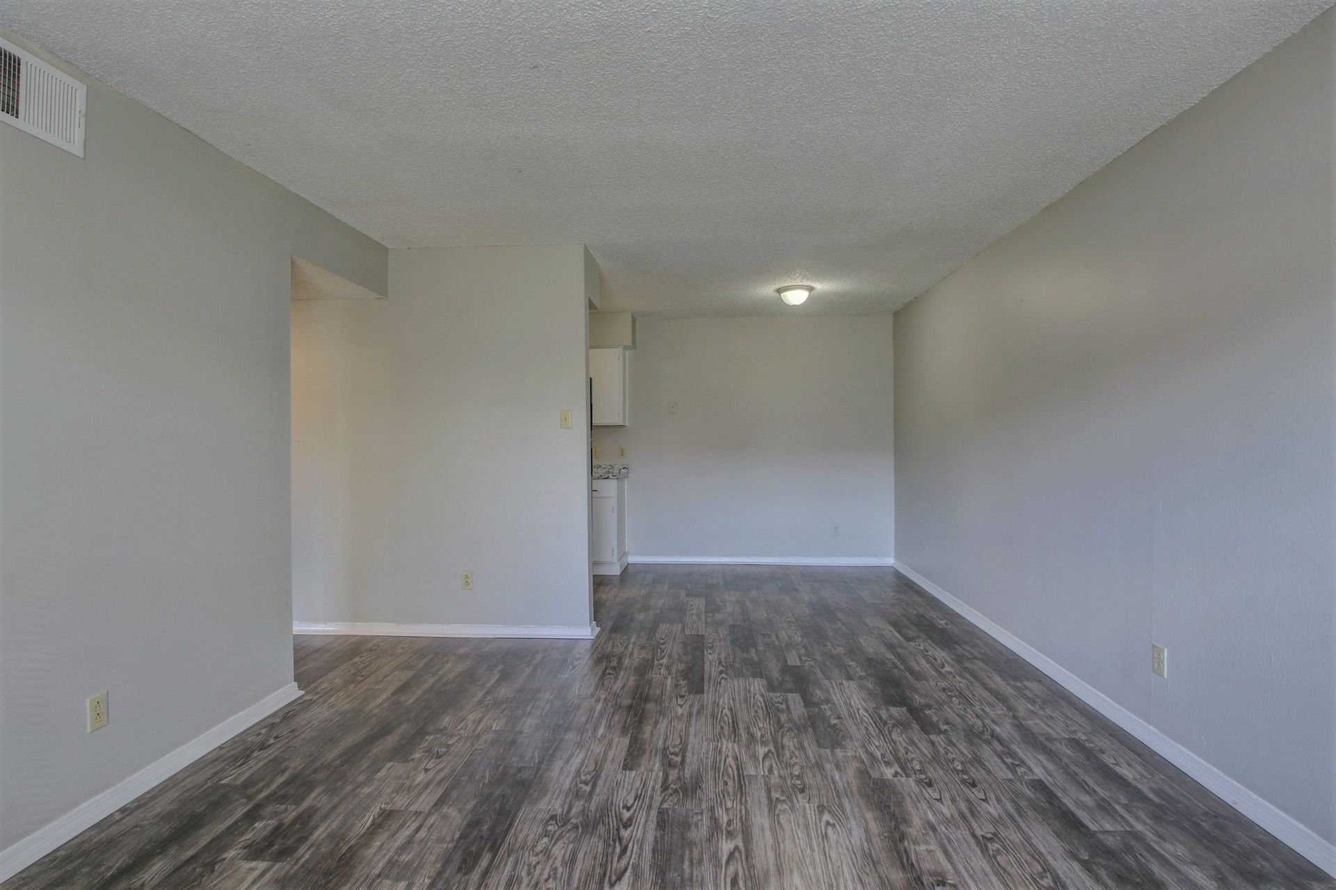 An empty living room with hardwood floors and white walls.