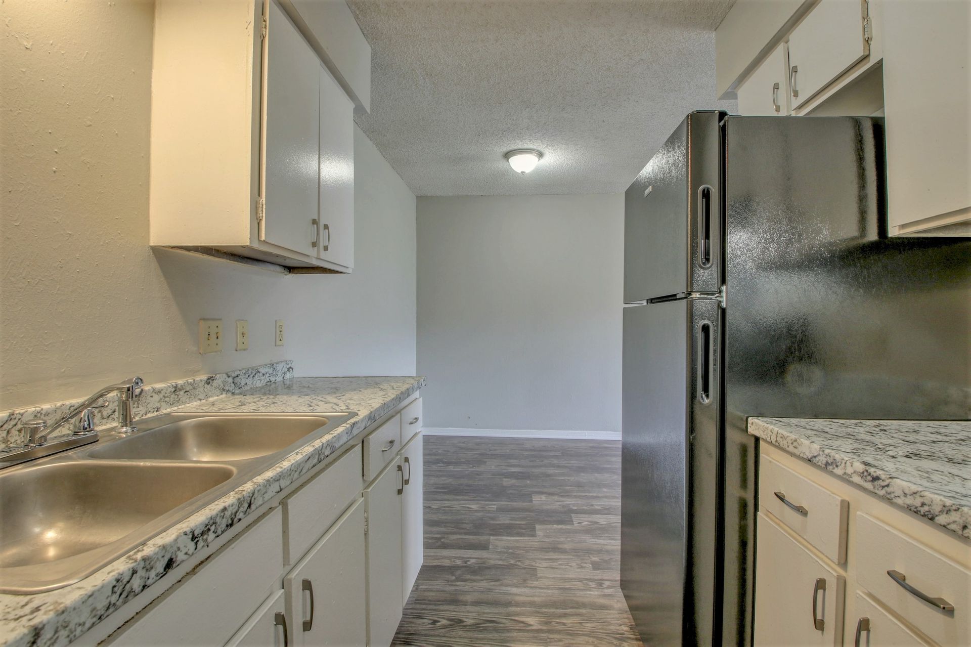 A kitchen with white cabinets and a stainless steel refrigerator