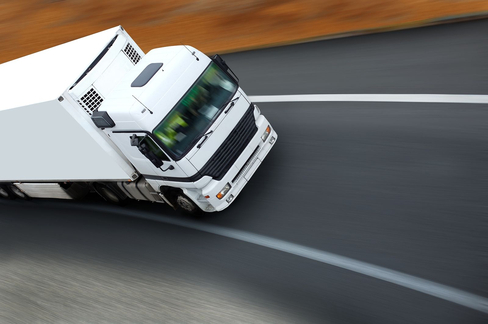 A white semi truck is driving down a curvy road