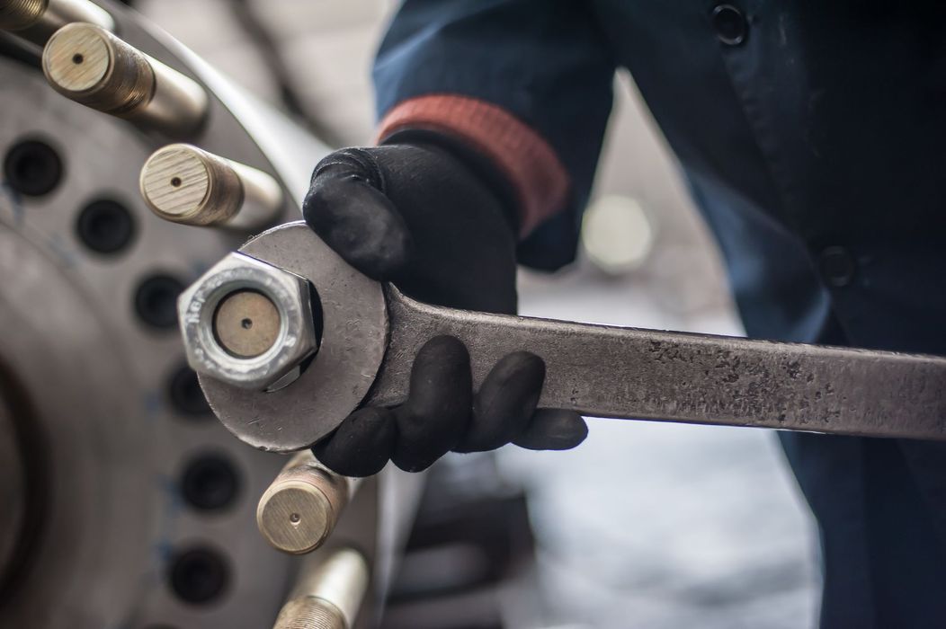 A close up of a person holding a wrench over a nut.