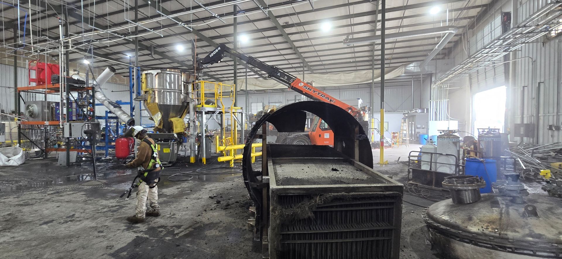Workers in a large industrial warehouse beside heavy machinery and equipment