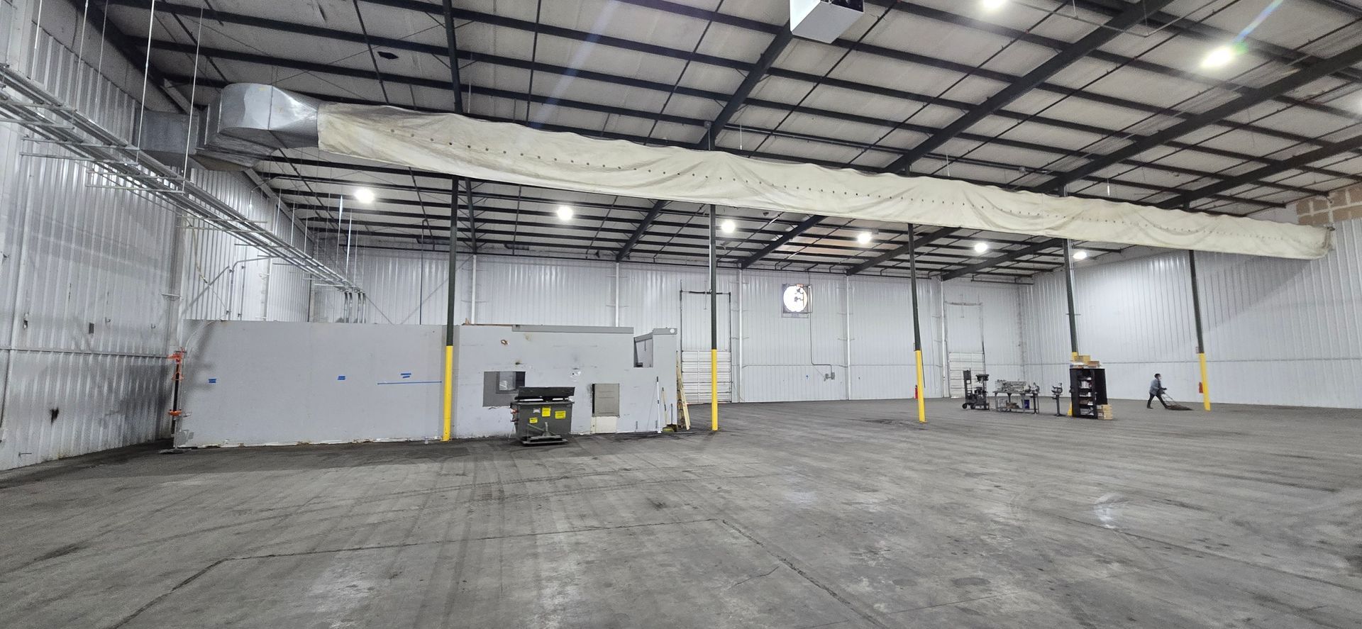 Empty industrial warehouse with high ceiling, concrete floor, and white walls
