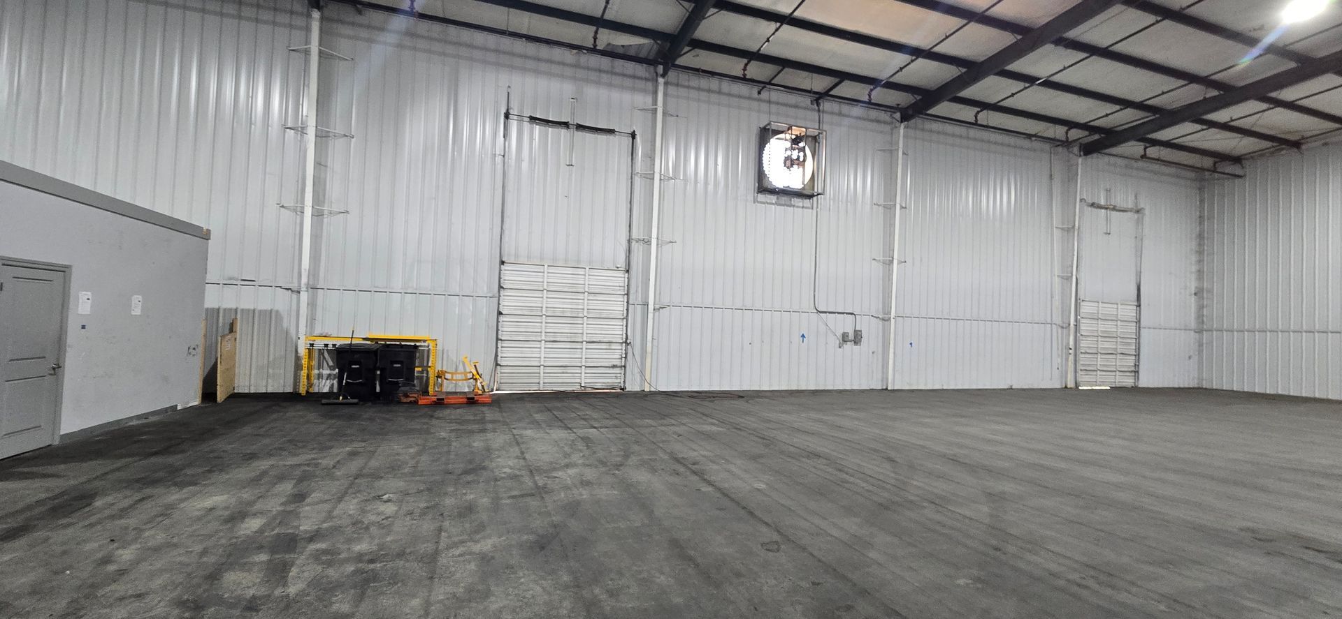 Empty warehouse interior with concrete floor, white walls, and high ceiling lights