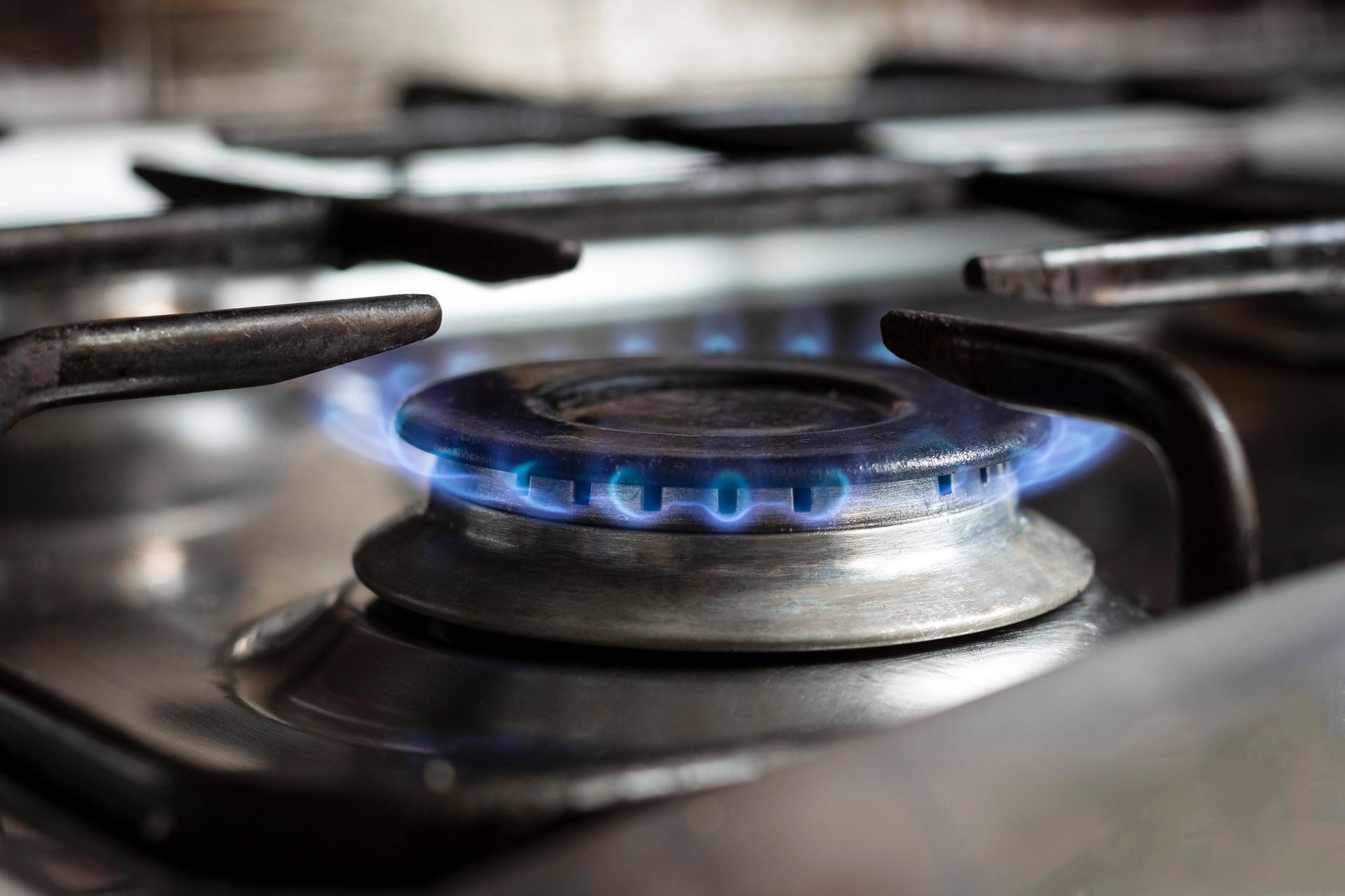 Fornello a gas acceso con fiamme blu.