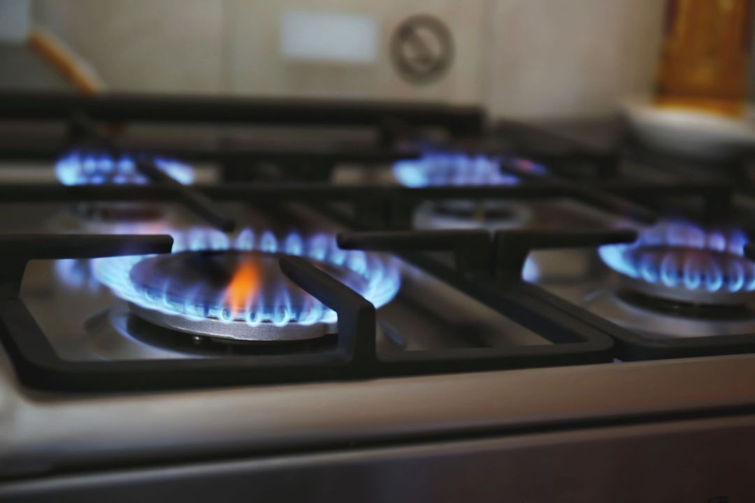 Piano cottura a gas con fiamme blu accese.