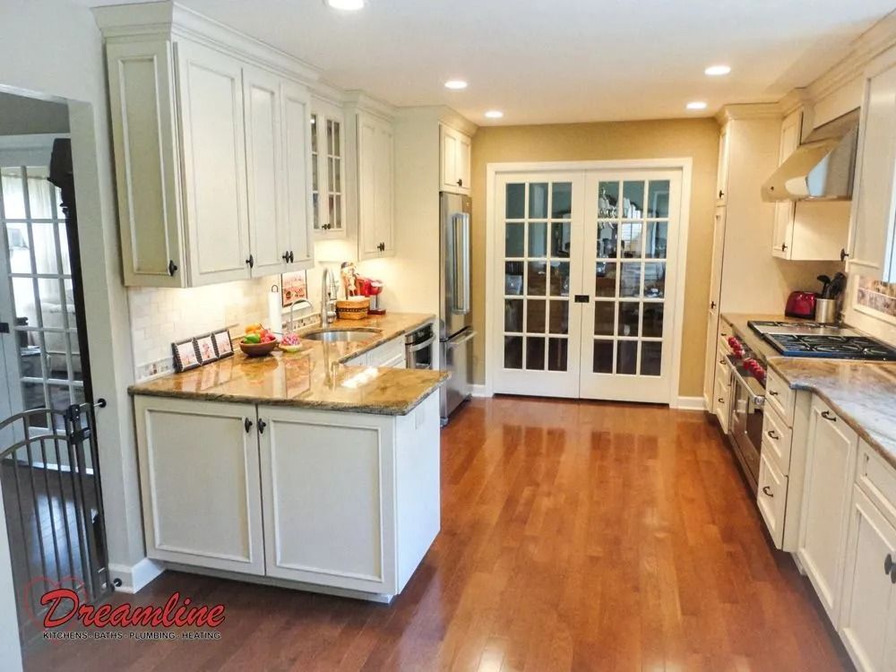 A kitchen with white cabinets , granite counter tops , stainless steel appliances and hardwood floors.