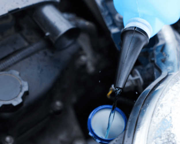A mechanic topping up radiator fluid