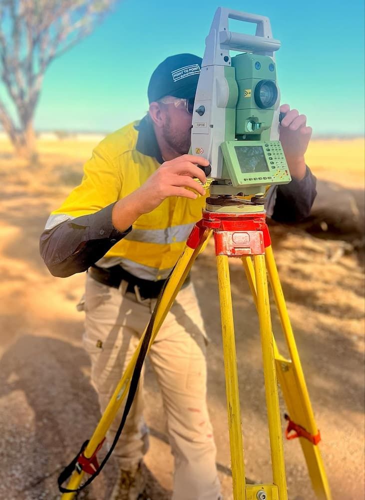 A Man in a Yellow Shirt is Using a Theodolite on a Tripod — Point to Point Surveying In Yarrawonga, VIC