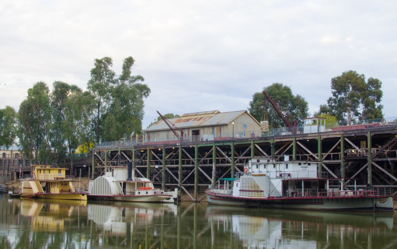 A Row Of Boats Are Docked In A Harbor With A Building In The Background — Point to Point Surveying In Kyabram, VIC
