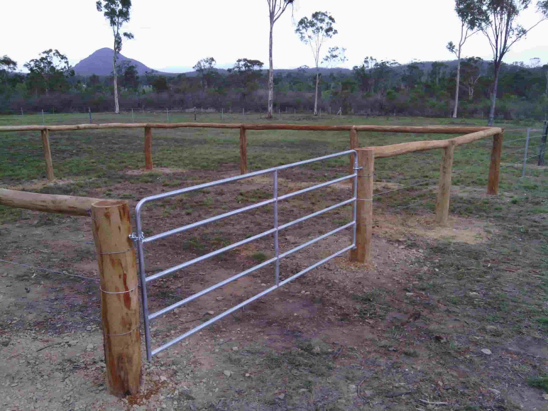 A Wooden Fence With A Metal Gate In The Middle Of A Field — Mini Excavator Hire & Rural Fencing In Bungundarra, QLD