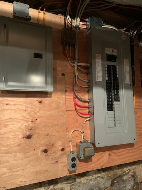 Panneau électrique et composants montés sur des panneaux de bois dans un sous-sol.