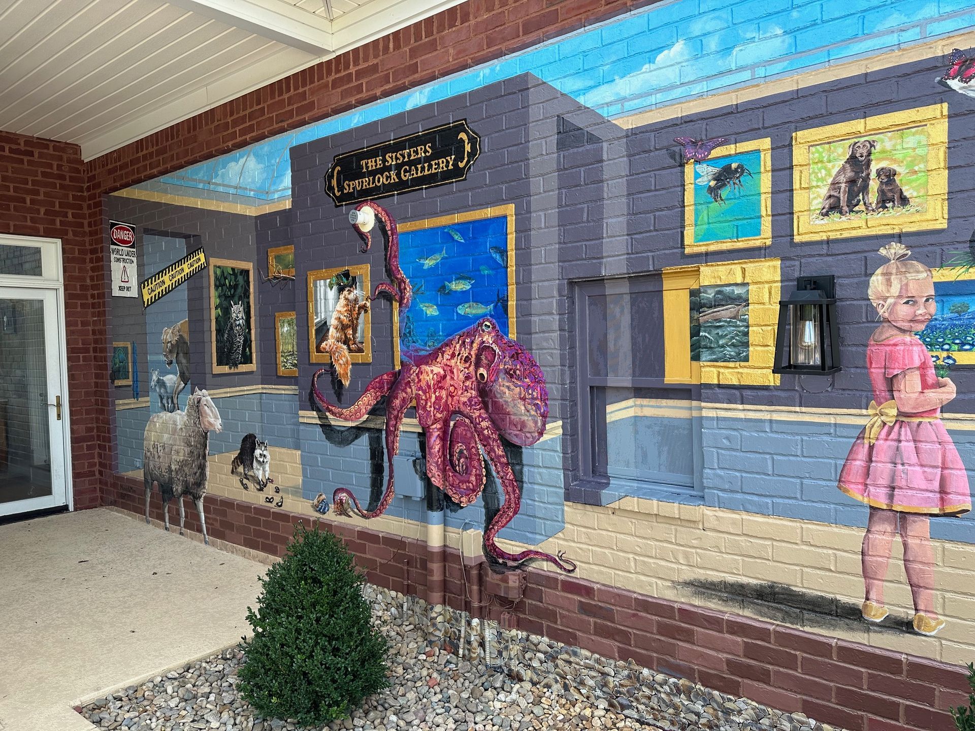 Left Side Focus of Painting Characters in Her Books Painted on This Exterior Brick Wall - Exterior and Residential Mural Art