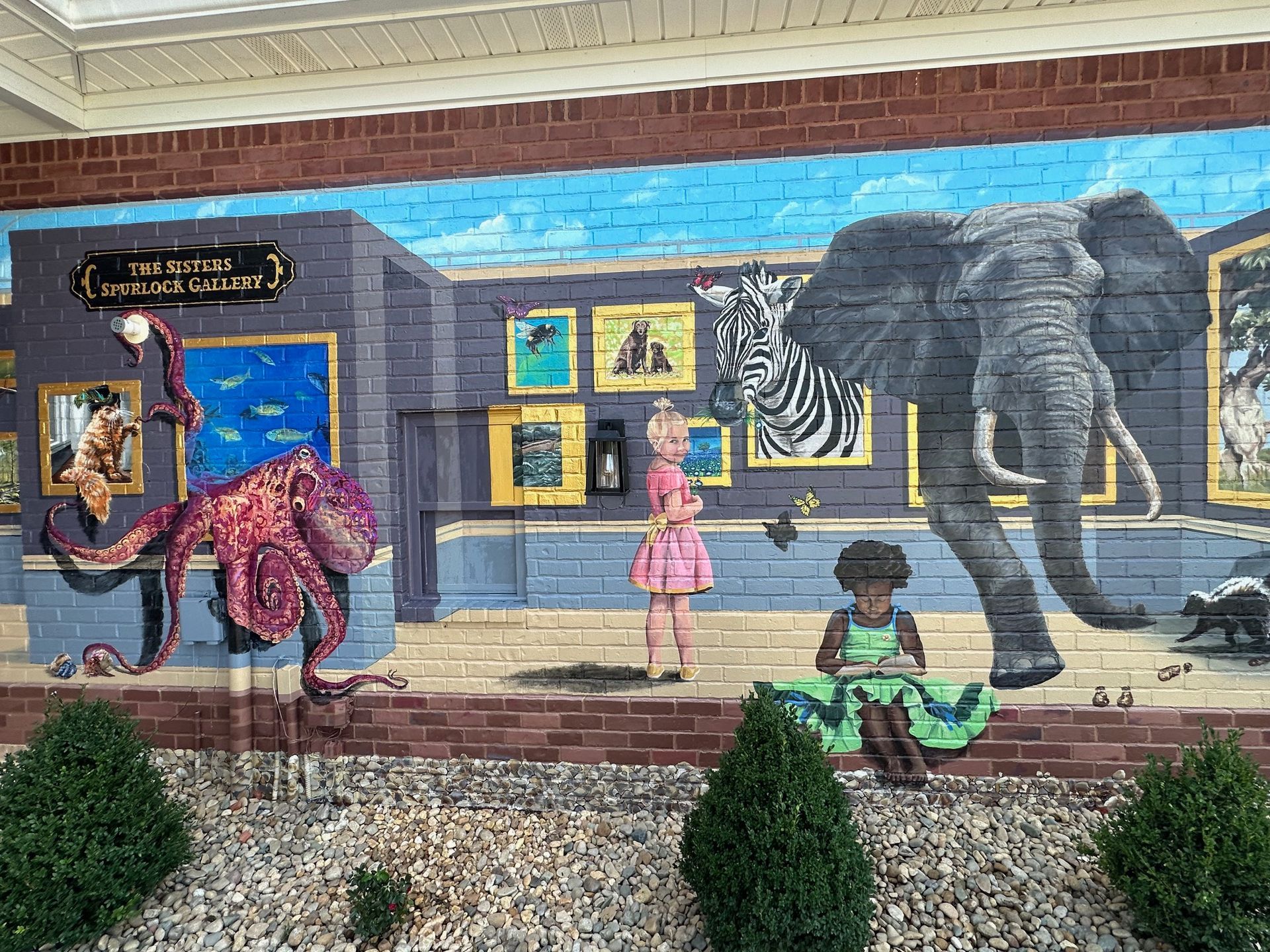 Center Focus of Painting Characters in Her Books Painted on This Exterior Brick Wall - Exterior and Residential Mural Art