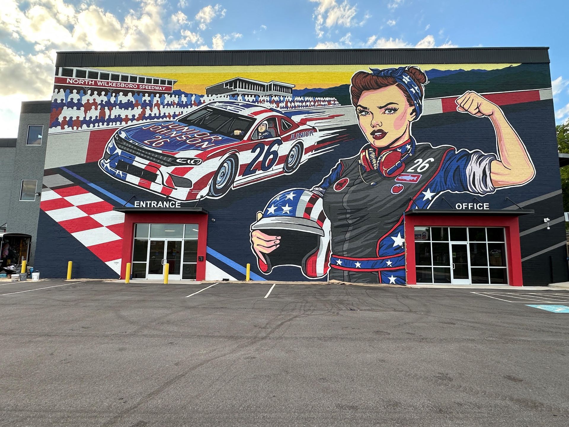 A large mural of a woman holding a helmet is on the side of a building.