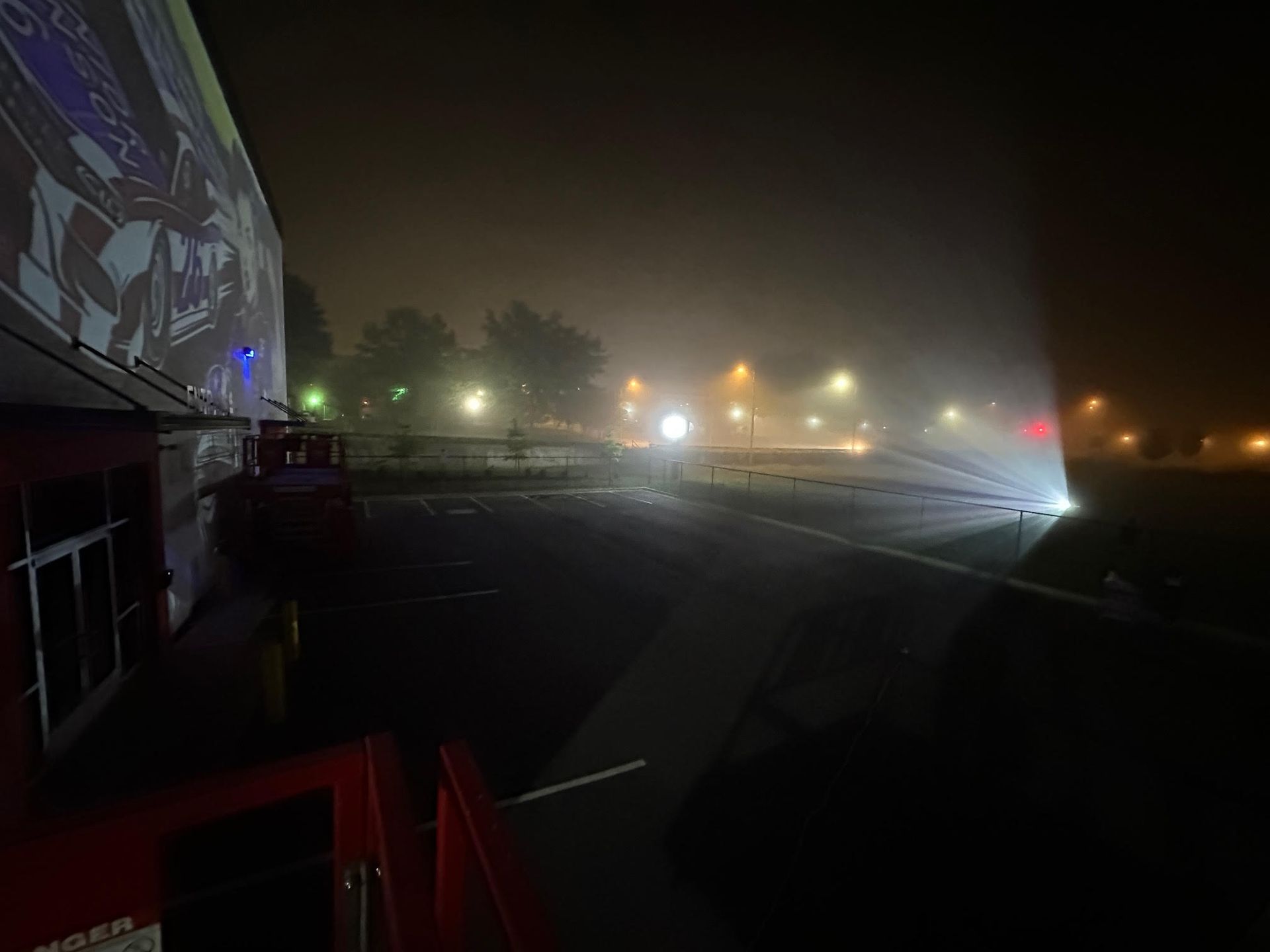 A large screen is projected onto a parking lot at night.