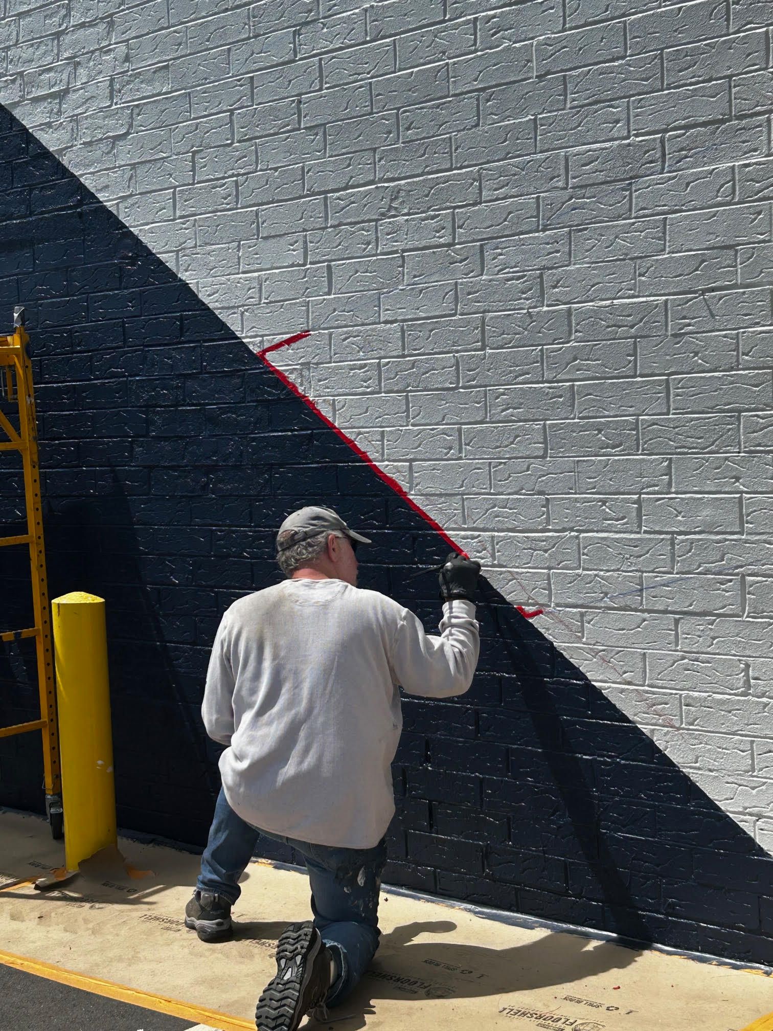 A man is measuring a brick wall with a tape measure.