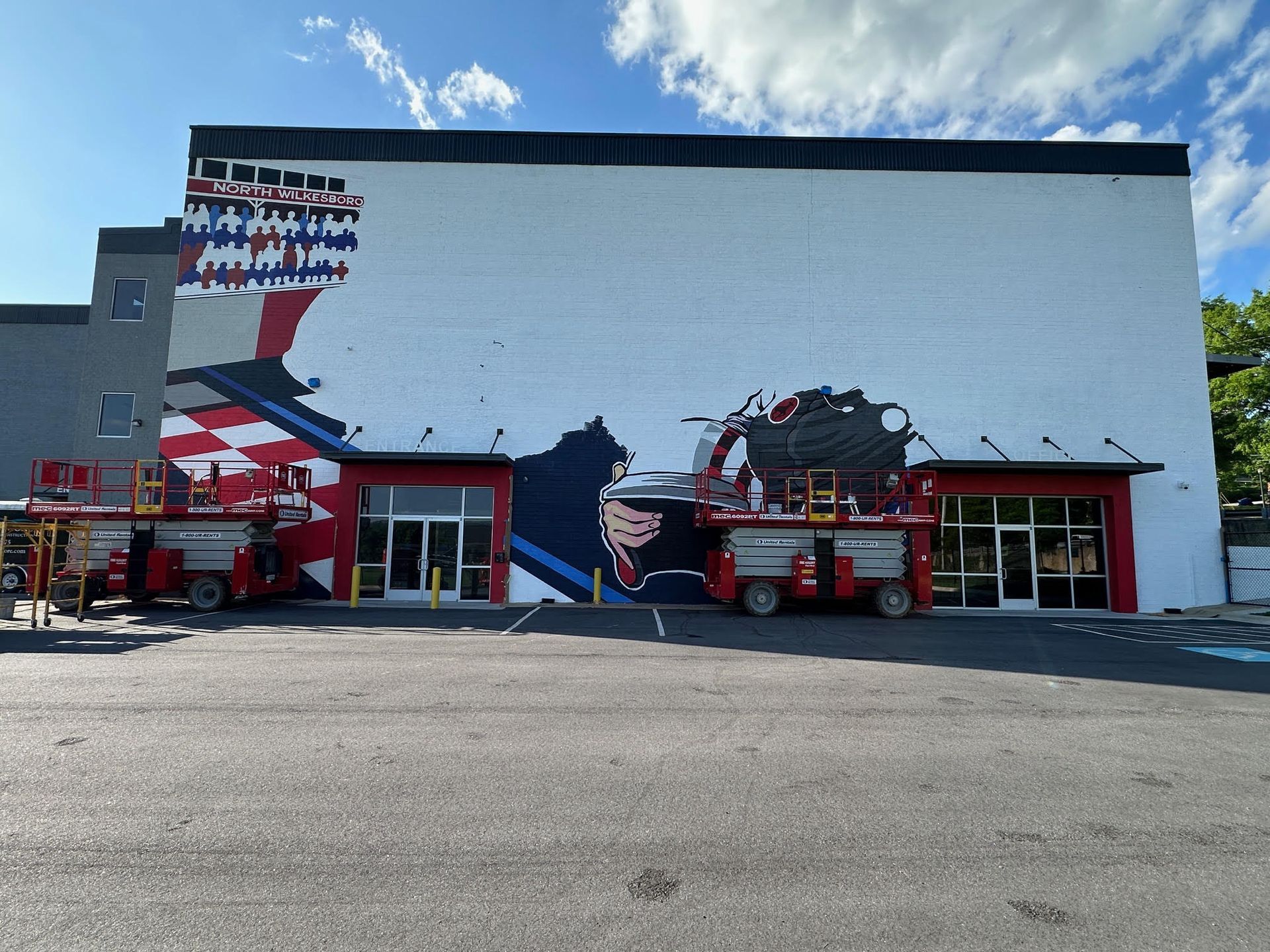 A large mural is being painted on the side of a building.