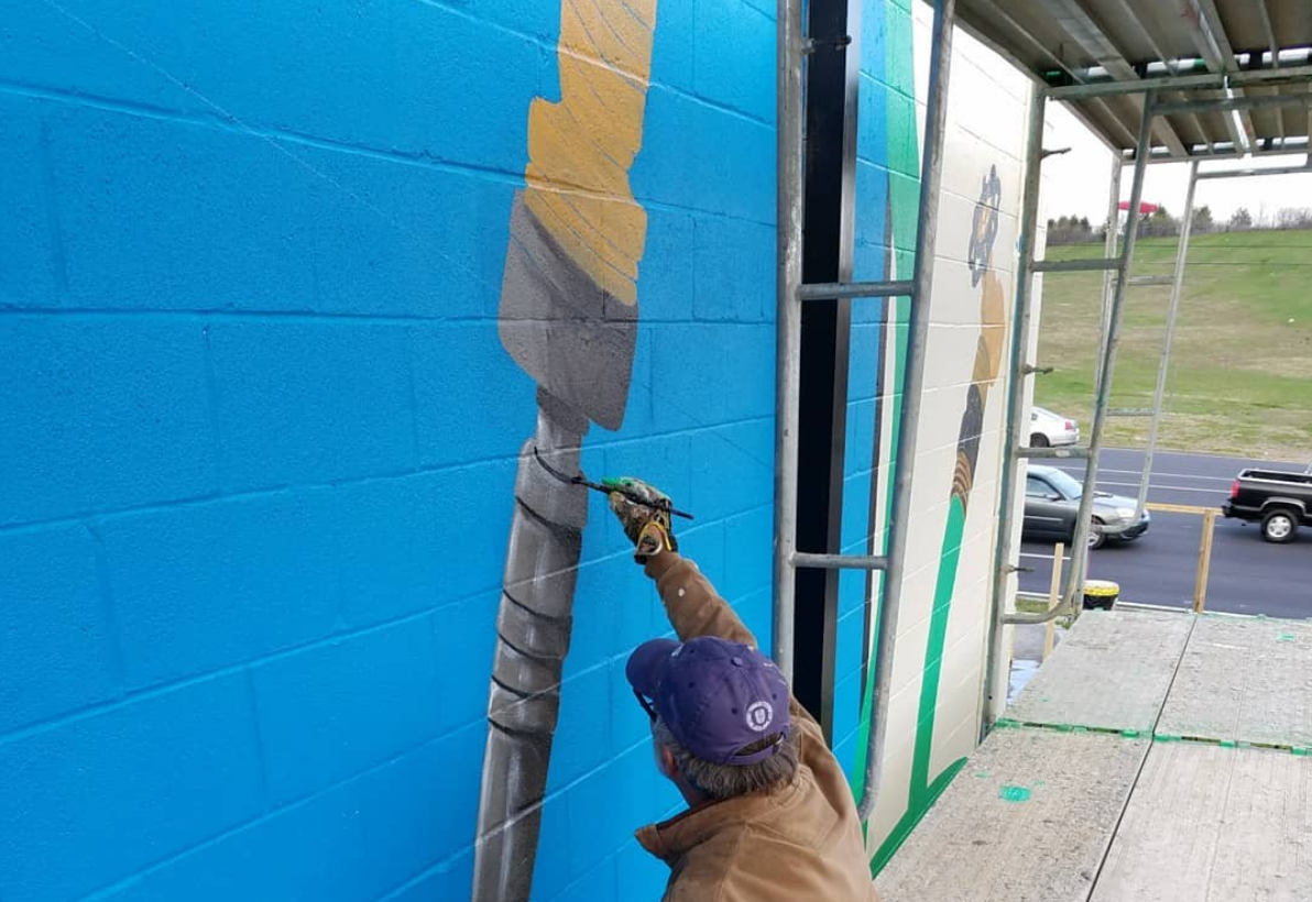 A person is painting a picture on a blue wall.