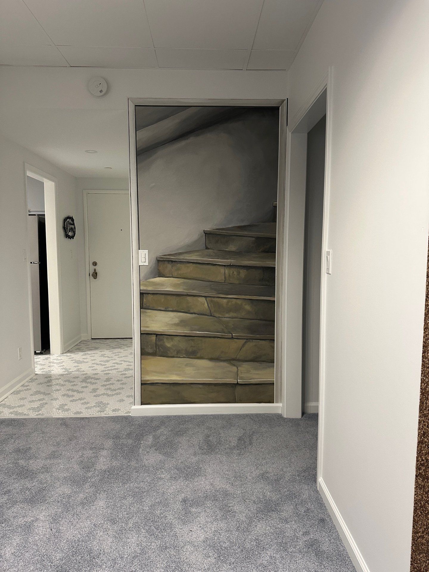 A hallway with a picture of a staircase on the wall.