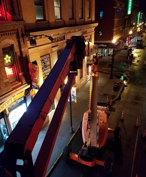 An aerial view of a city street at night with a crane in the foreground