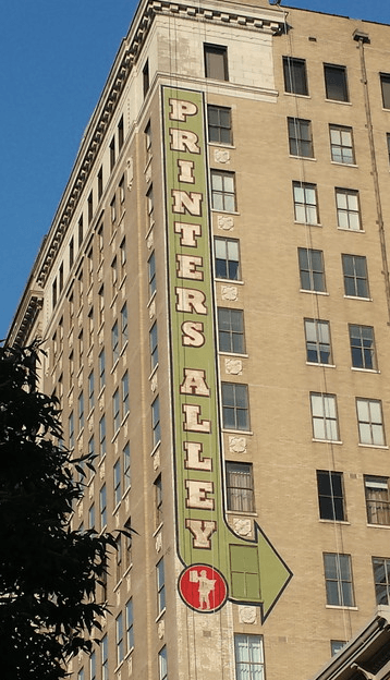 A tall building with a sign that says printers alley