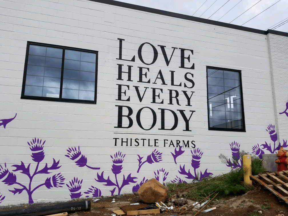 A mural on the side of a building that says love heals every body