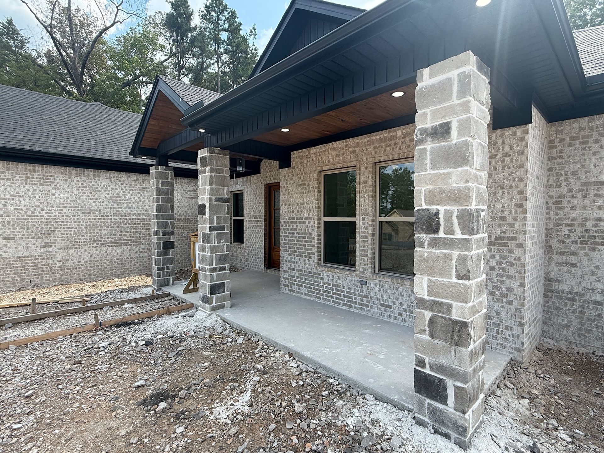 Side view of a white brick house with black trim and new windows.
