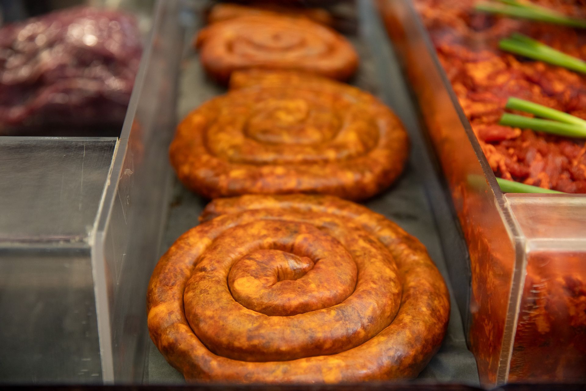 Spiral-shaped chorizo sausages in a display case, showcasing the red meat.