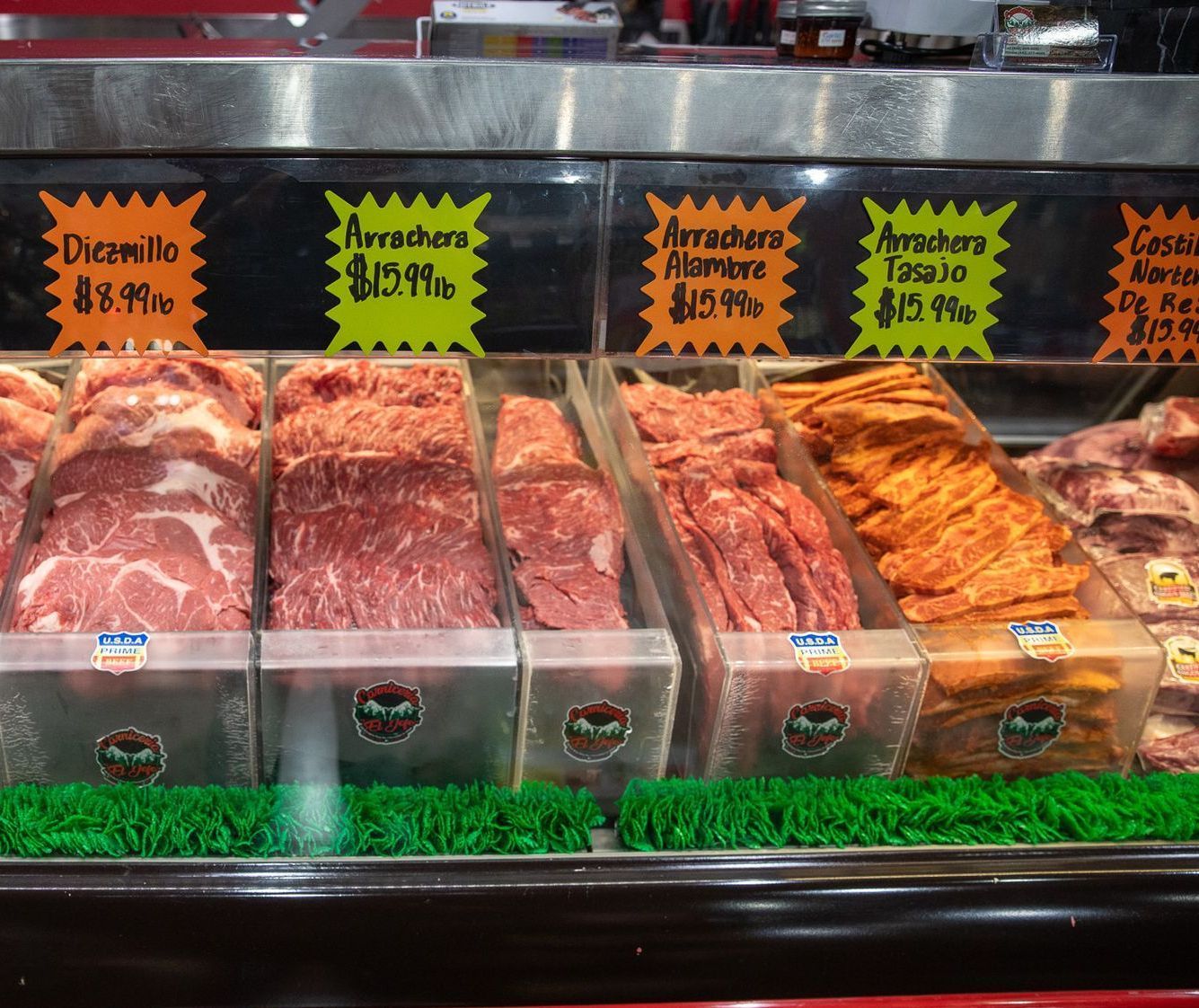 Meat display case with various cuts, including skirt steak, with price tags in Spanish.