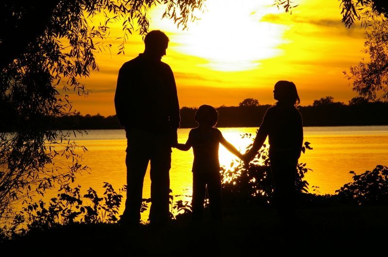 A family holding hands in front of a lake at sunset